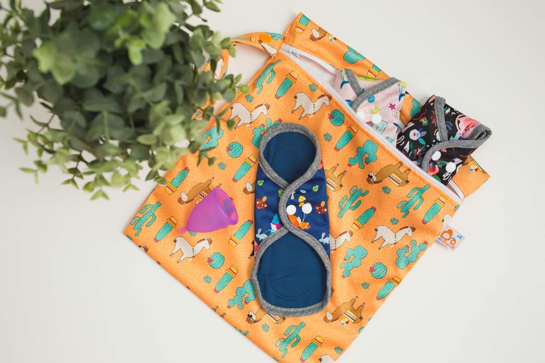 two folded reusable menstrual pads and a snapped reusable pad with zipper bag