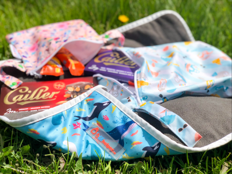Cailler chocolate bars in patterned snack bags on grass with waterproof mat