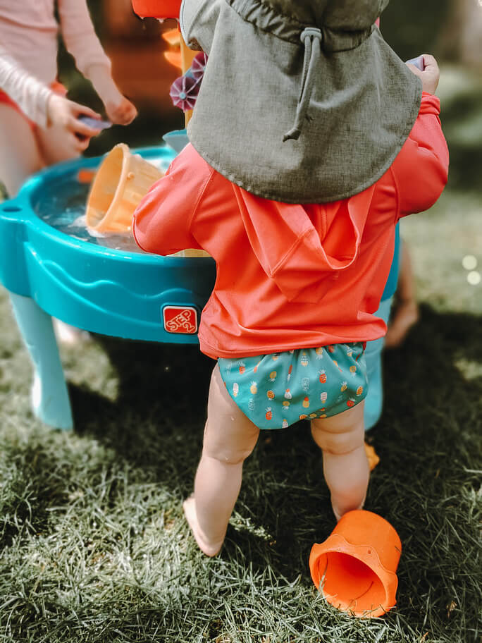 a baby at a small pool wearing a non-disposable swim diaper