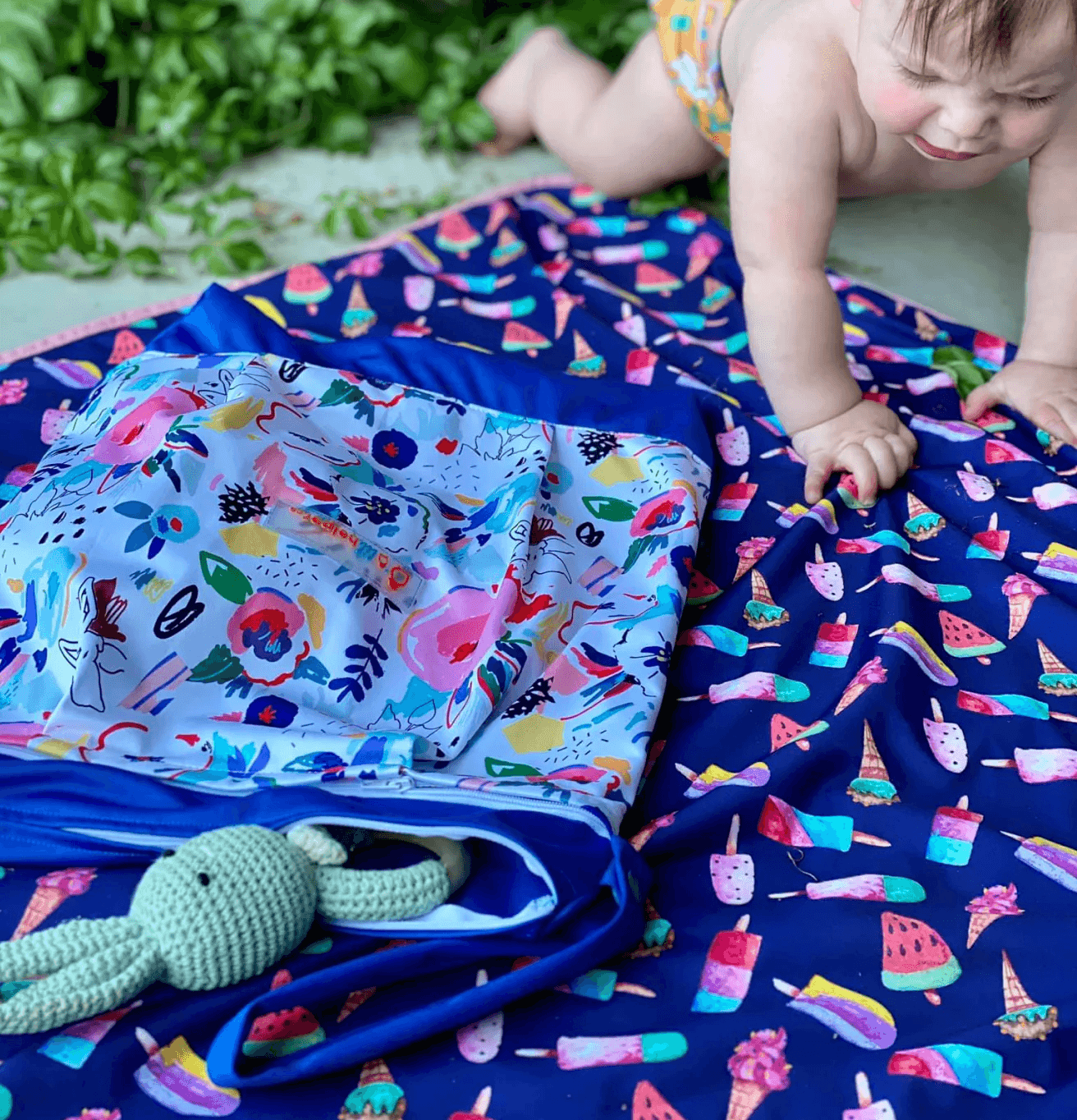 a baby crawling on a blanket next to a wet bag