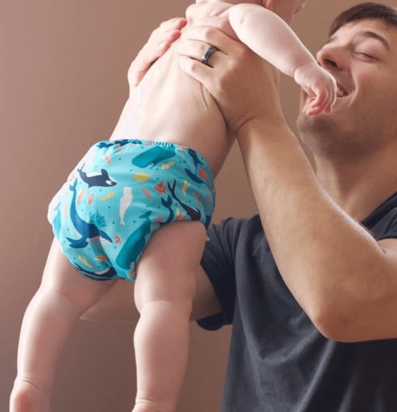 a dad lifting up a baby wearing a cloth diaper